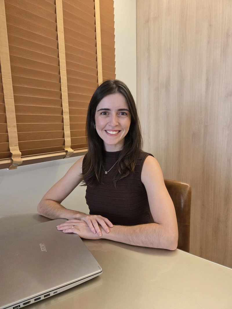 Dra. Raquel Cosso sentada em seu consultório